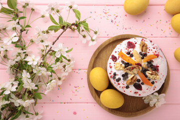 Traditional easter cakes with colorful sprinkles, with eggs, a bunny figurine, and spring flowers on pink wooden background