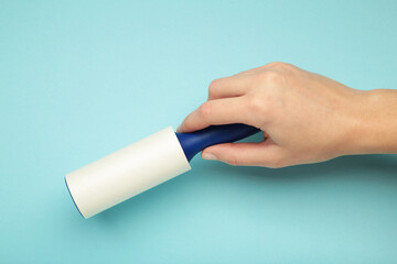 Woman holding lint roller on blue background. Top view
