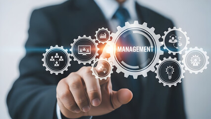 A businessman interacts with a digital interface displaying interlocking gears representing management and business processes including teamwork growth and innovation