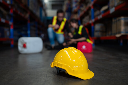 Mature foreman in workwear giving first aid to asian women staff suffering after working injury in warehouse, Injury at work.