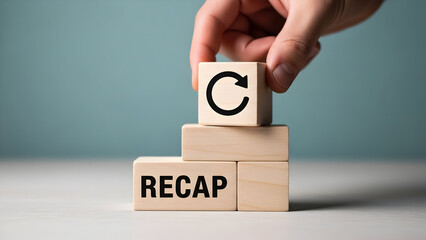 A hand places a refresh symbol on wooden blocks spelling recap
