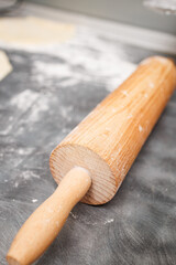 Close-up of a wooden rolling pin resting on a floured surface. A natural, textured kitchen scene ideal for baking and recipe visuals