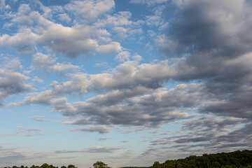 Obraz premium Cloud formation over a rural landscape during the late afternoon showcasing a bright blue sky and varying cloud textures