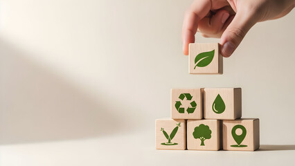A hand places a wooden block with a leaf symbol atop a stack representing environmental themes