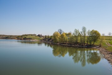 Tranquil scene of a vast lake and shoreline under a bright blue sky