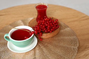 Cup of healthy viburnum tea on coffee table in living room, closeup