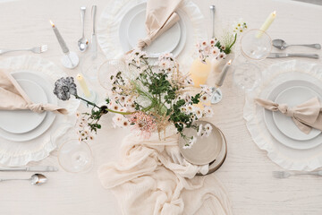 Beautiful table setting with bouquet of flowers and candles in light dining room, top view