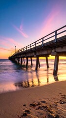Fototapeta premium Long pier stretches towards the horizon at sunset with beautiful colors