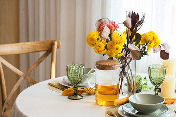 Beautiful table setting with bouquet of flowers, tea and candles in light dining room