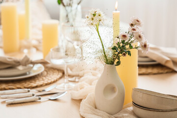 Bouquet of beautiful flowers and candles on served dining table, closeup