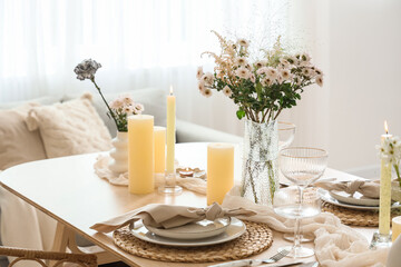 Beautiful table setting with bouquet of flowers and candles in light dining room