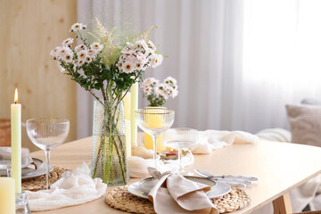 Beautiful table setting with bouquet of flowers and candles in light dining room