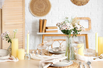 Beautiful table setting with bouquet of flowers and candles in light dining room