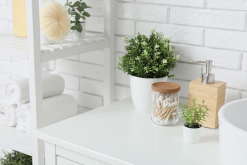 Artificial plants with cotton buds and soap on table in bathroom
