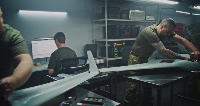 Adult Woman Engineer in Military Uniform Meticulously Assembles Large UAV Alongside Male Colleagues. Concept of Gender Diversity and Professional Expertise in Defense Engineering. Dolly Shot.