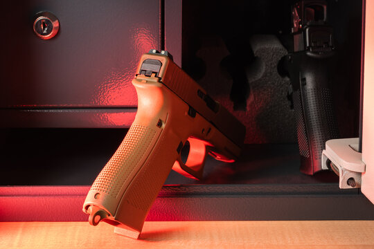 Secure storage solution: Two semi-automatic pistols, one in coyote tan, safely locked inside a personal metal gun safe, emphasizing home protection and safety.