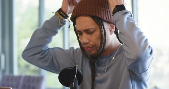 Mid adult male lifting headphones, adjusting cups and listening to test signal at home studio mic