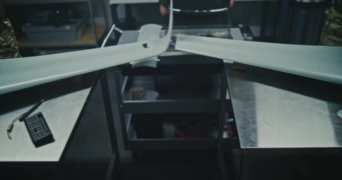Professional Team Wears Military Style Attire While Meticulously Building High Grade Reconnaissance Drones. Concept of Serious, Strategic Nature of Production For National Security. Top View.