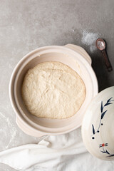 overhead view of focaccia dough proofing in a claypot, top view of a high hydration focaccia bread dough resting in a donabe, process of making high hydration focaccia