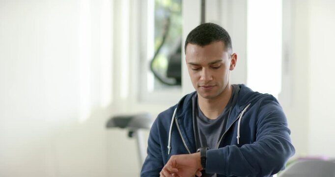 After completing workout man sitting on therapy bench tapping smartwatch to confirm workout metrics