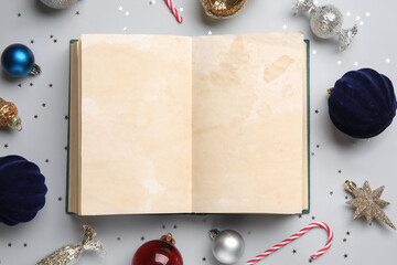 Blank book with Christmas balls and candy cane on grey background