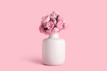 Vase with artificial peony flowers on pink background
