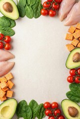 Top view flat lay frame of raw chicken breast, green avocado, spinach and sweet potato cubes on beige stone background with copy space. Vertical healthy keto food concept for weight loss nutrition