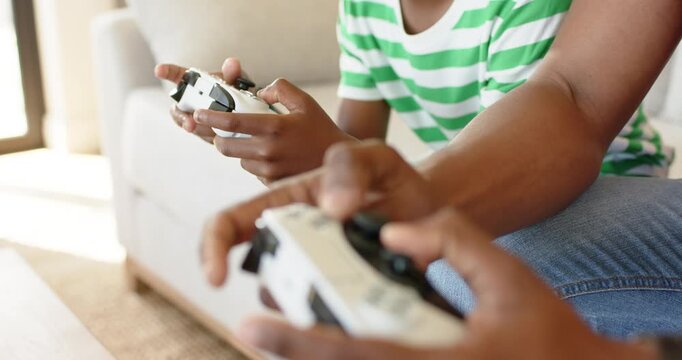 Game starting as friends leaning forward and pressing analog sticks and buttons for gaming session