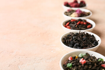 Bowls with different dry fruit tea on pink grunge background, closeup