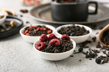 Bowls with dry fruit tea on grey grunge background, closeup