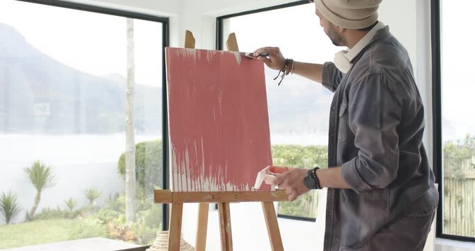After loading brush with red paint artist is painting horizontal strokes for red layer in studio