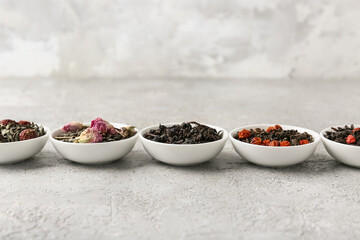 Bowls with different dry fruit tea on grey grunge background, closeup