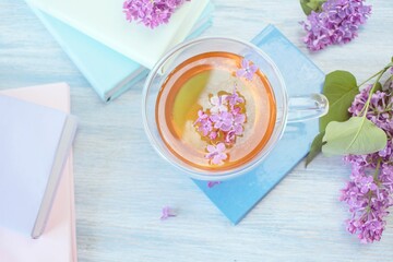 Lilac, books and cup of tea on wooden background