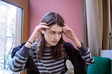 Young man concentrating or experiencing stress, young woman in emotional state of stress, holding her head.