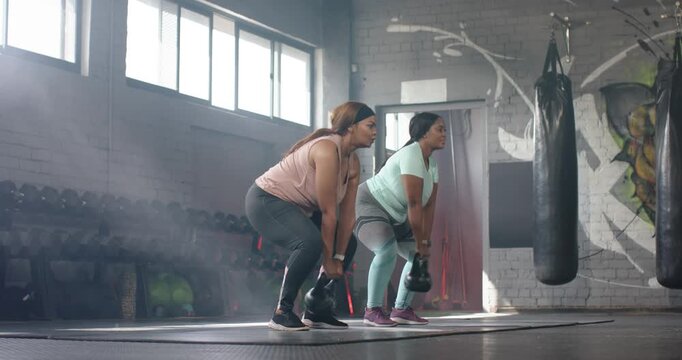 After raising kettlebells, diverse female friends doing swings and hinge squats during gym training