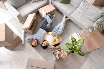 Happy young couple lying in rented apartment on moving day, top view