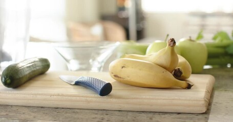Camera is moving closer and shifting focus on cutting board to sharpen bananas and knife