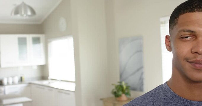 Daylight streaming through window drawing man standing in kitchen and smiling subtly, copy space