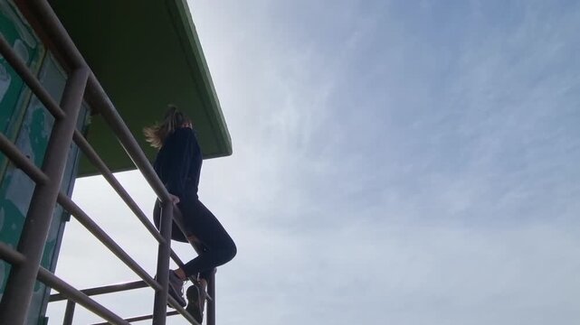 Woman climbing a guard tower railing at Pico de la Gorra, Gran Canaria.