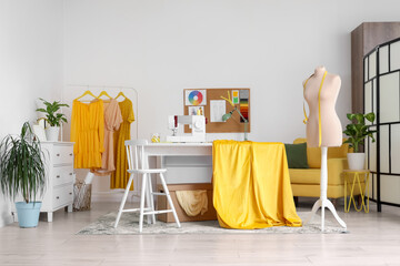 Interior of light atelier with mannequin, tailor's workplace and clothes rack