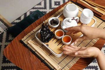 Female hands with Asian tea set on table in room, closeup