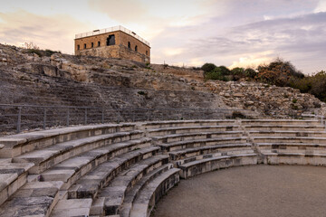 Curved stone tiers of the Roman amphitheater at Zippori National Park in Galilee, Israel, with a hilltop fortress above under a soft evening sky, showcasing ancient masonry and archaeology 