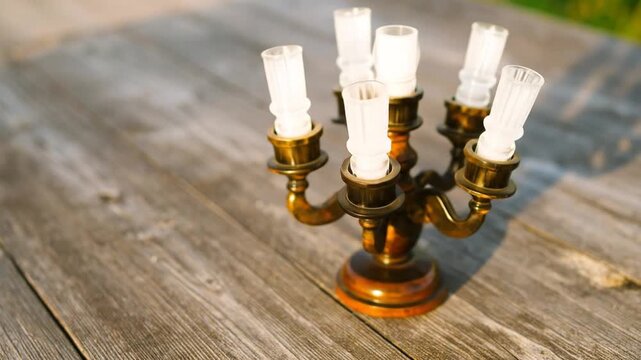 A candelabra sits on a weathered wooden surface, glowing in the sunlight