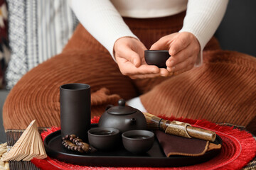 Woman with Asian tea set on table at home, closeup