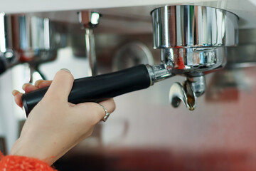 Hand attaching portafilter to coffee machine close-up