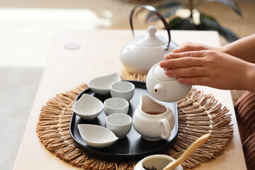Female hands pouring Asian tea on table at home, closeup