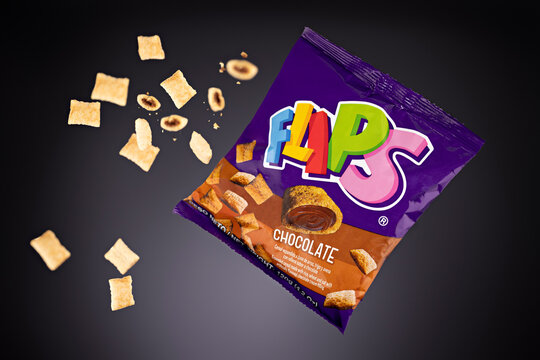 Bag of Flips chocolate-filled cereal snacks Made from expanded rice, wheat, and oat, accompanied by floating cereal pieces that highlight their texture and a chocolate cream filling