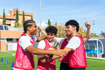 Young diverse soccer players celebrating their victory, holding a trophy and cheering on the football field
