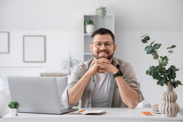 Fototapeta premium Young man with laptop at desk in office
