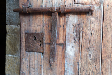 Old, rusty, sturdy metal bolt on a wooden door